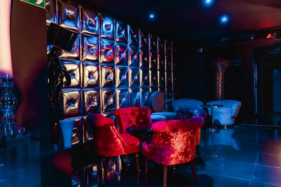 Sala más privada de la planta inferior con butacas rojas y mesas bajas