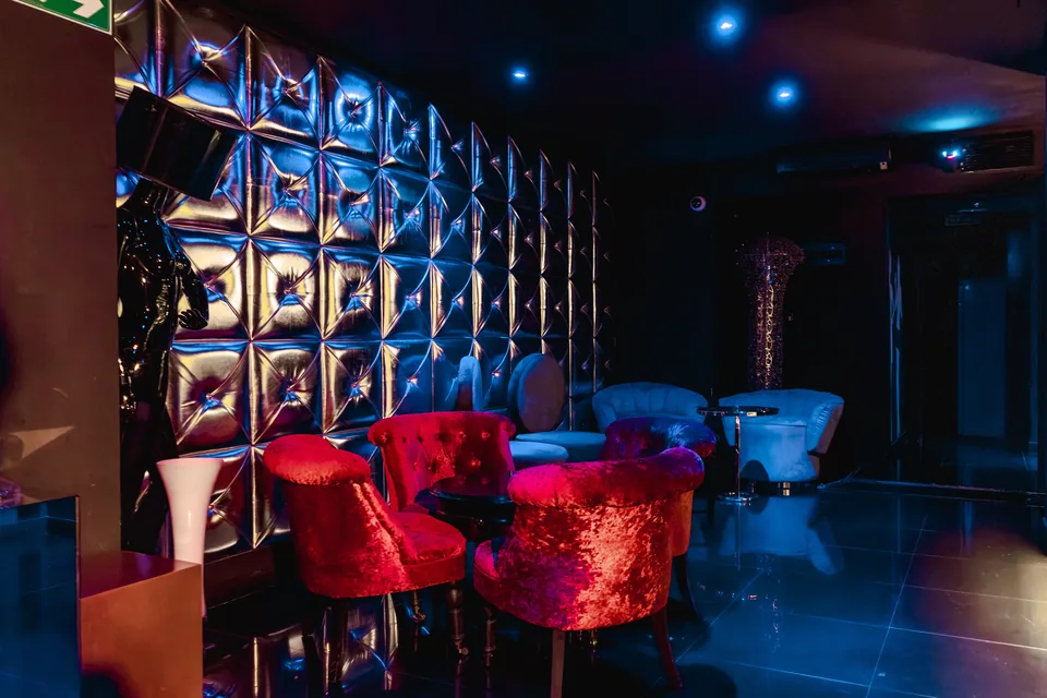Salón de la planta inferior con butacas rojas, asientos azules y pared geométrica